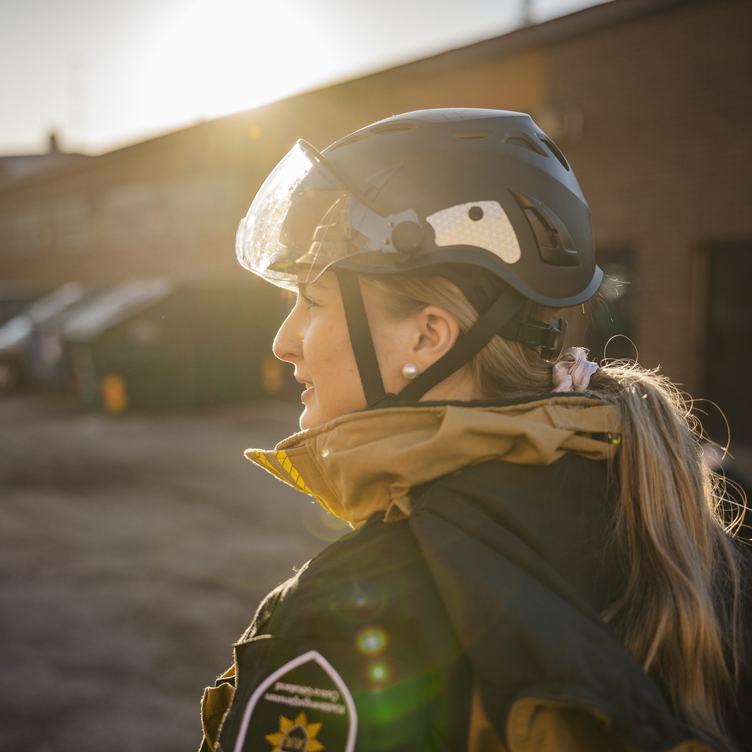 En brandman fotad från sidan. Hon är klädd i larmställ och hjälm.