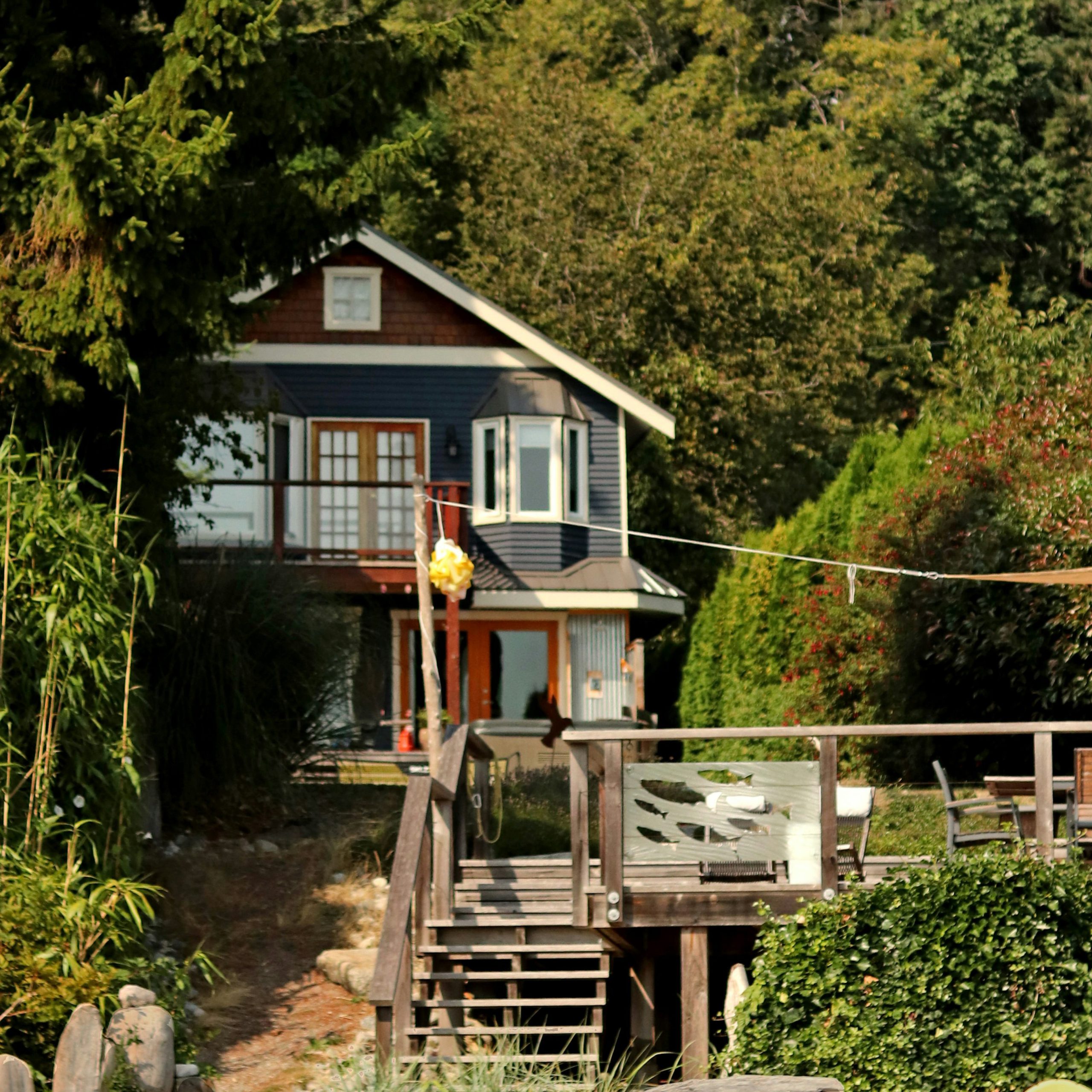 Bild på en sommarstuga, mitt i skogen, på en solig dag.