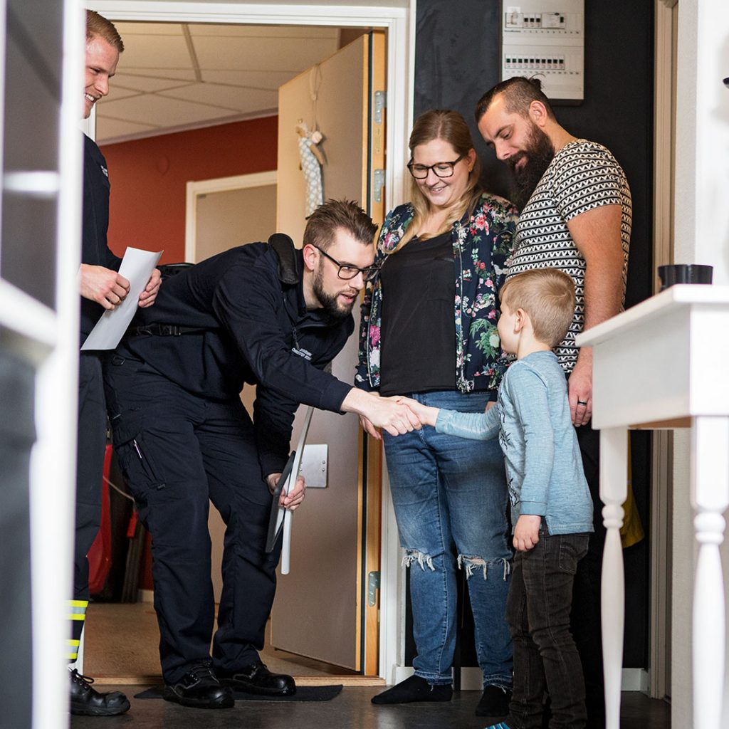 En familj tar emot personal från räddningstjänsten i sin hall i en lägenhet.
