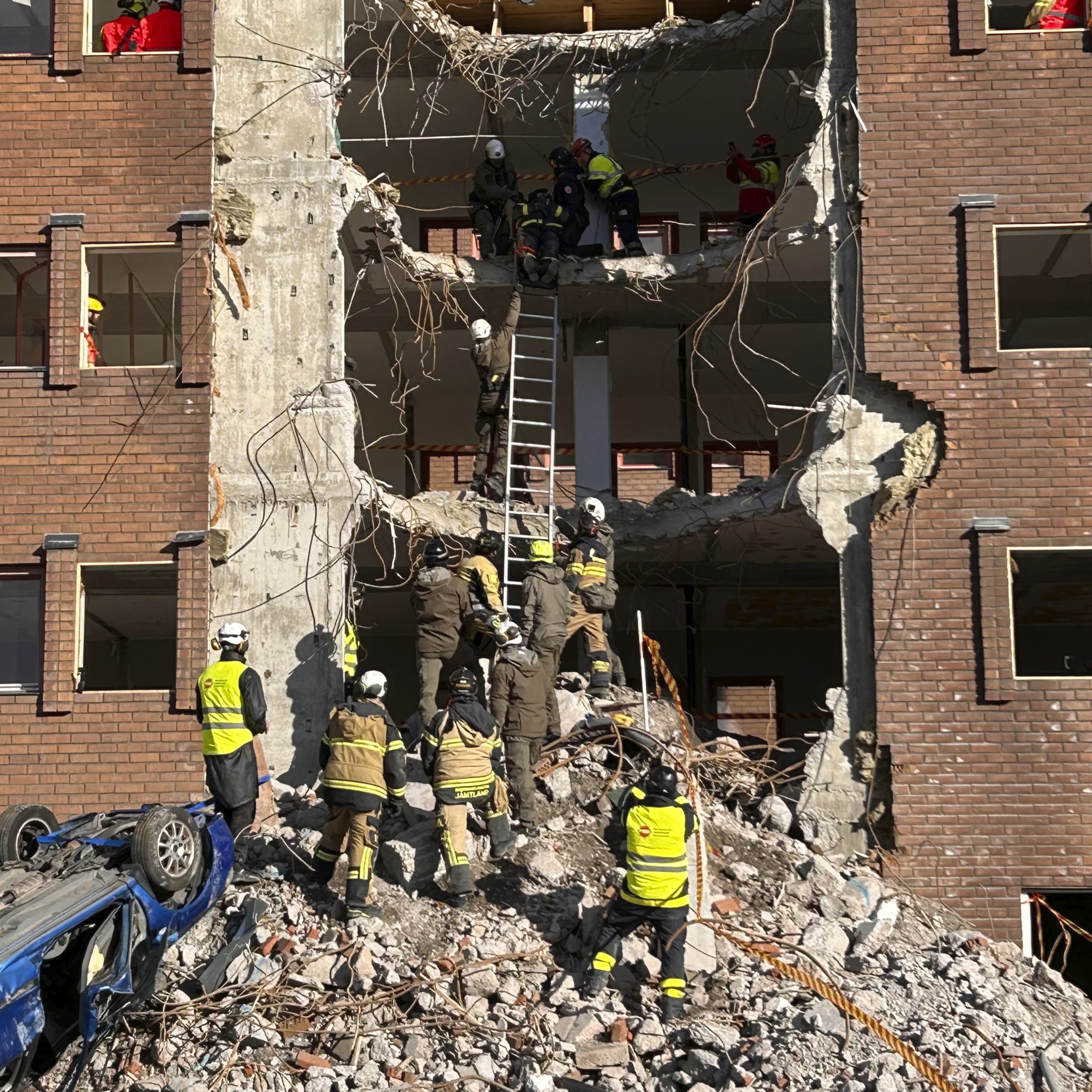 En grupp brandmän övar räddning i rasmassor i ett kollapsat höghus.