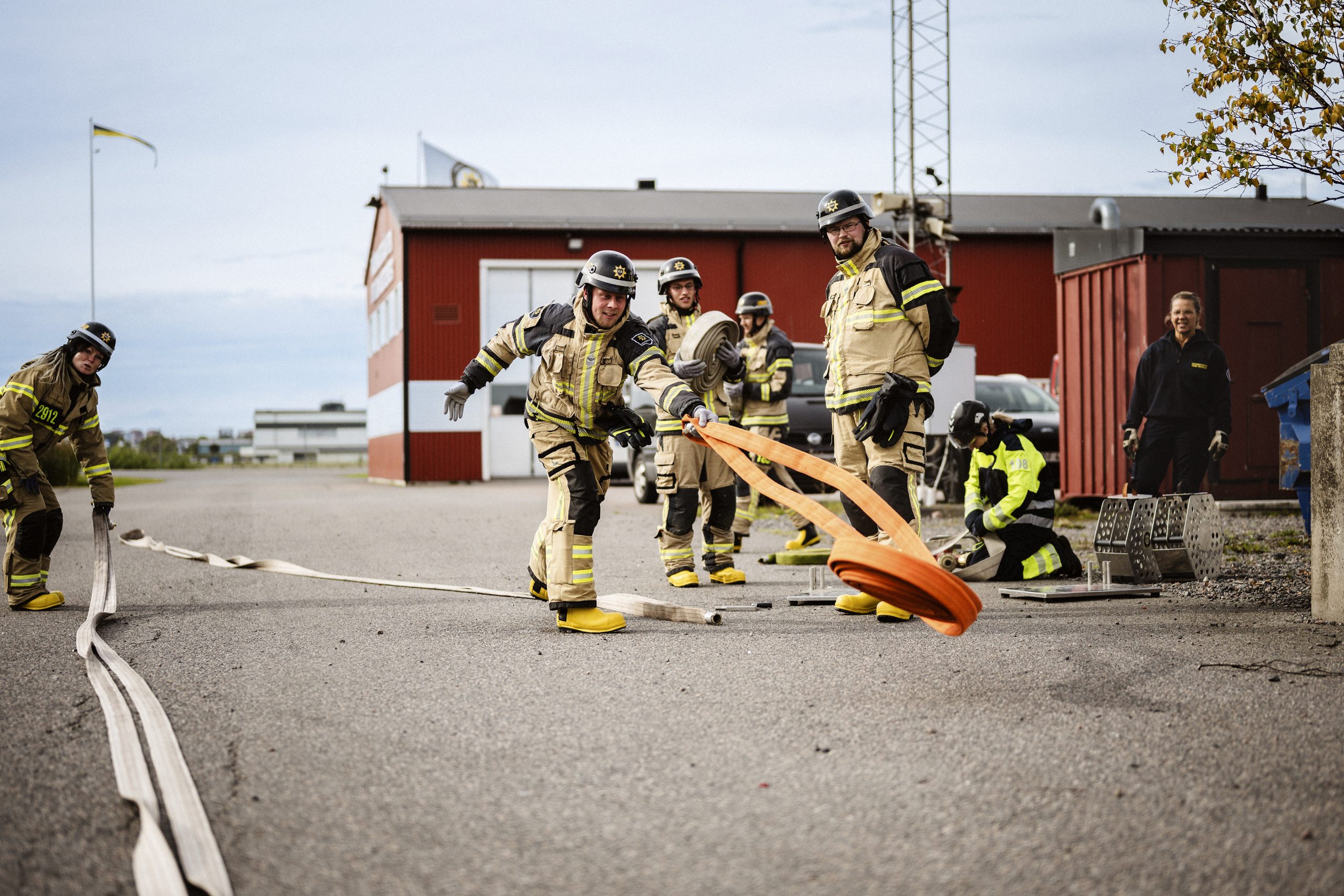 En grupp brandmän rullar ut slang under en övning.